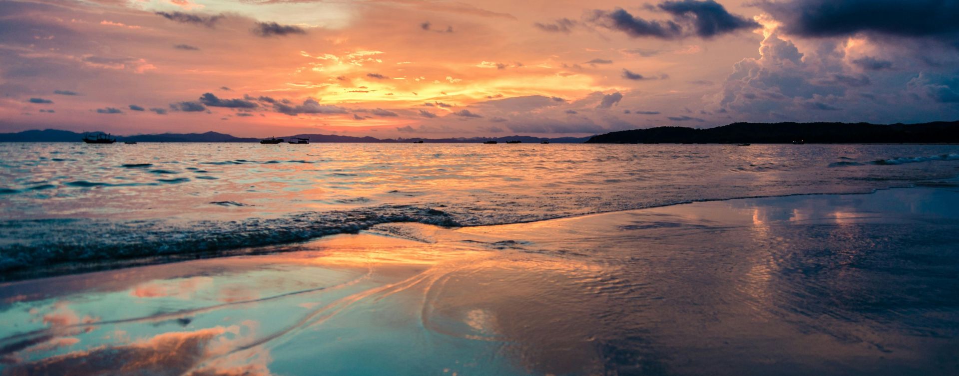 Stunning sunset over the ocean with vibrant reflections on a tranquil beach.